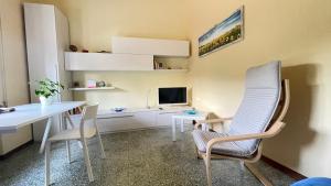 ein Wohnzimmer mit einem Tisch, Stühlen und einem TV in der Unterkunft Tra gli olivi in Lucca