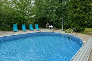 a large swimming pool with blue chairs and a gazebo at Apartmány orlík in Klučenice