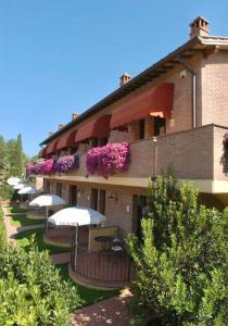 um edifício com guarda-chuvas e flores ao lado em Casa Vacanze con piscina a San Gimignano em San Gimignano