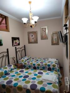 a bedroom with two beds and a chandelier at Apartamento Carmen en Muxía in Muxia