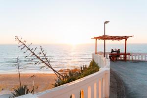 two people sitting at a picnic table on the beach at Alfaiate Beach House in Santa Cruz