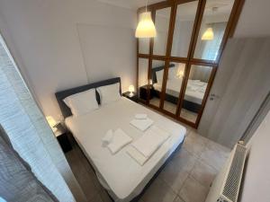 a small bedroom with a white bed and a mirror at The traveler's house in Thessaloniki