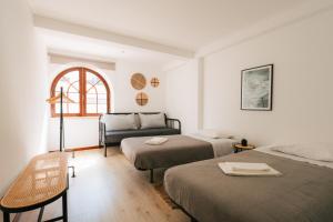 a room with two beds and a couch and a table at Alfaiate Beach House in Santa Cruz