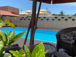 a patio with an umbrella and chairs and a swimming pool at Pousada da Mel - Canasvieiras Floripa in Florianópolis