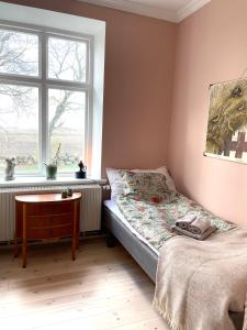 a bedroom with a bed and a table and a window at Tullesbo Sätesgård in Sjöbo