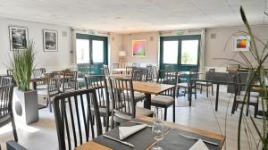 a dining room with tables and chairs and windows at Les Chevaliers des Balances in Saint-Aubin