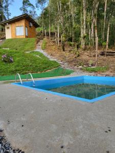 una piscina de agua con una casa en el fondo en Pousada Cantinho da Tia Amanda, en Pinheiral