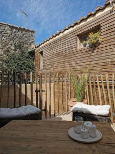 un patio con una valla de madera y una mesa con tazas en La Planque/Terrasse - entre Nîmes/Pont du Gard, en Marguerittes