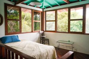 una camera da letto con finestre, un letto e un tavolo di Blue Butterfly House a Pavones