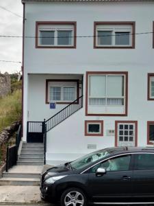 a black car parked in front of a white building at Apartamento Carmen en Muxía in Muxia