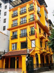 a yellow building with balconies on a city street at Aisha HOTELS and APARTMENTS in Hanoi