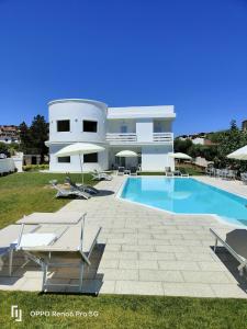 ein großes weißes Haus mit Pool und Stühlen in der Unterkunft Al Mare da Francesca in Olbia