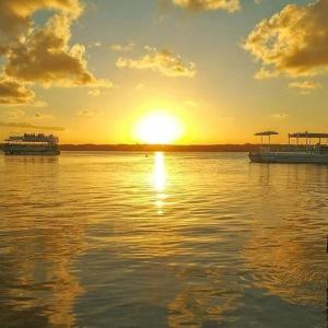 a sunset over a large body of water with two boats at Pousada e Hostel sol e mar in João Pessoa