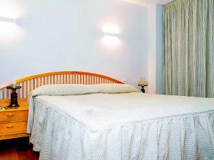 a bedroom with a white bed with a wooden headboard at Apartamento Deluxe zona Baja con Garaje in Sierra Nevada