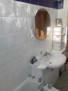 Baño blanco con lavabo y espejo en Top Floor. Top Notch. Tranquil Treat. Stone's throw from Thames., en Maidenhead