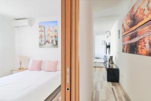 1 dormitorio con 1 cama con sábanas blancas y almohadas rosas en Playa apartamento, en Málaga