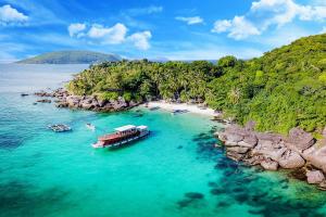 a boat in the water next to a beach at Apec Mandala HaDoFinn in Tuy Hoa