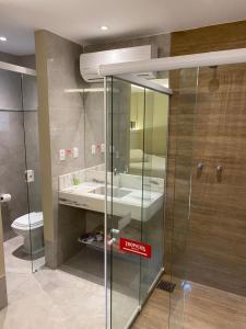 uma casa de banho com uma cabina de duche em vidro e um lavatório. em Trópicos Motel em Natal