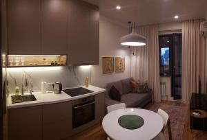 Cozy Urban Retreat في ألماتي: مطبخ وغرفة معيشة مع طاولة وأريكة