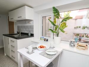 a white kitchen with a table with a bowl of fruit at Lane Cottage in Cardigan