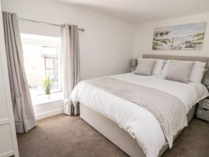 a white bedroom with a large bed and a window at Lane Cottage in Cardigan