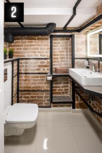 a bathroom with a brick wall and a toilet and a sink at The Heart of Lviv Apartments - Lviv in Lviv