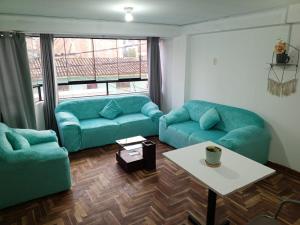 een woonkamer met twee blauwe banken en een tafel bij DEPARTAMENTO AMOBLADO EN CUSCO in Cuzco