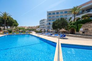 a swimming pool with chairs and a building at Casablanca Apartments, Santa Ponsa in Santa Ponsa