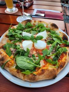 a pizza with greens on a white plate on a table at Landhotel & Gaststuben Zum Hasen in Bad Saulgau
