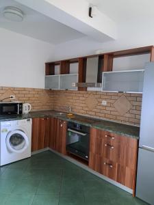 eine Küche mit Holzschränken, einer Waschmaschine und einem Trockner in der Unterkunft Ogrodowe Noclegi 2 