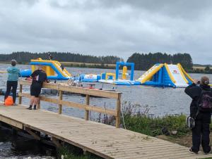 a group of people standing on a dock with some slides at Loch's Heaven 67 in Kirkcowan