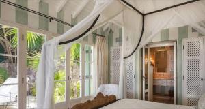 a bedroom with a bed with a canopy and windows at Breathtaking 6 BR Villa with Infinity Pool in Pointe Milou