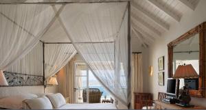 a bedroom with a canopy bed with a large window at Breathtaking 6 BR Villa with Infinity Pool in Pointe Milou