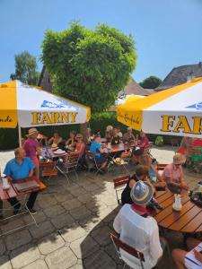 un grupo de personas sentadas en mesas bajo sombrillas en Landhotel & Gaststuben Zum Hasen en Bad Saulgau