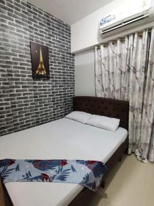 een slaapkamer met een bed en een bakstenen muur bij Cozy 1 bedroom with Balcony in Manilla