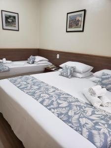 two beds in a hotel room with towels on them at Hotel Orleans in Petrópolis