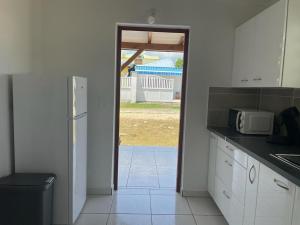 una cucina con forno a microonde e una porta che conduce a un cortile di L’Eucalyptus a Sainte-Rose