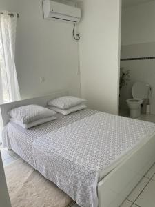 a white bedroom with a bed and a toilet at L’Eucalyptus in Sainte-Rose