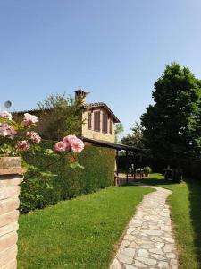 un chemin en pierre devant une maison avec des fleurs roses dans l'établissement Il Tiglio Bianco, à Sienne