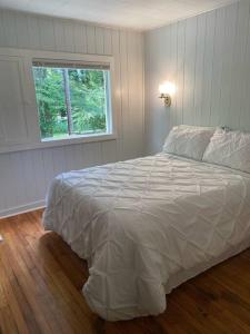 1 dormitorio con cama blanca y ventana en The Garden Cottage, en Hendersonville