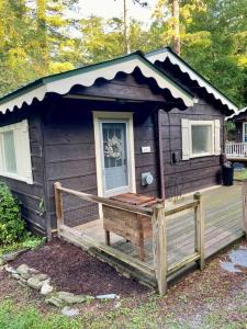 a small brown house with a porch and a fence at The Garden Cottage in Hendersonville +6 photos
