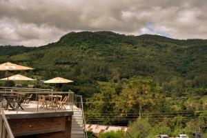 a patio with tables and umbrellas and a mountain at Pousada Stein Haus in Picada Cafe