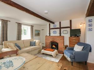 a living room with a couch and a fireplace at Horseshoe Cottage in Pentney