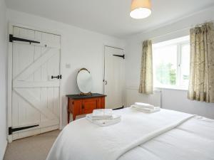 a bedroom with a white bed and a mirror at Horseshoe Cottage in Pentney