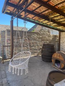 a white swinging chair in a patio with a barrel at Kuća na selu “ANNA” in Feketić
