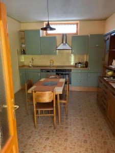 a kitchen with green cabinets and a table and chairs at Kuća na selu “ANNA” in Feketić
