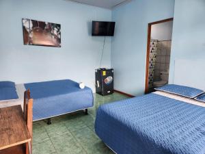 a room with two beds and a television in it at Hotel y Restaurante El Marino in Santa Cruz