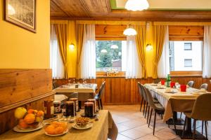un restaurante con mesas y sillas con comida. en Hotel Bijou en Valtournenche