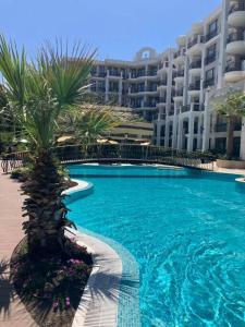 a large swimming pool with palm trees in front of a building at Apartament Harmony in Sunny Beach +12 photos