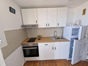 a kitchen with white cabinets and a sink and a refrigerator at Une parenthèse au Frioul in Marseille